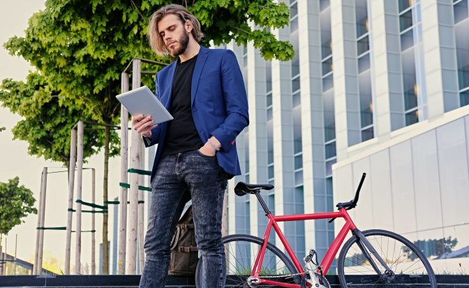A man holds tablet PC with red single speed bicycle on background.