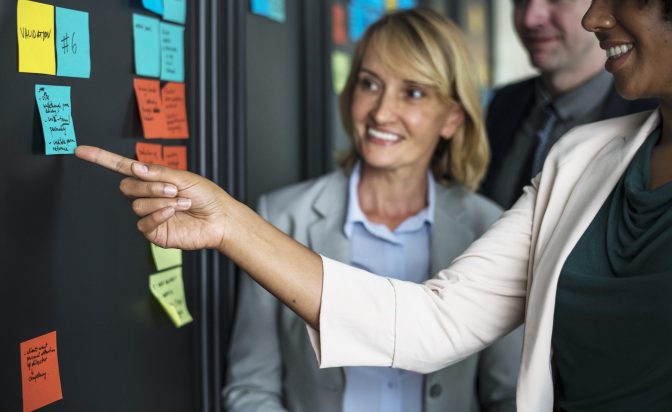 Businesspeople planning tasks with sticky notes